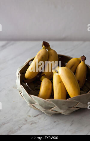 Baby Bananen in den Korb auf dem weißen Marmor Tisch Stockfoto