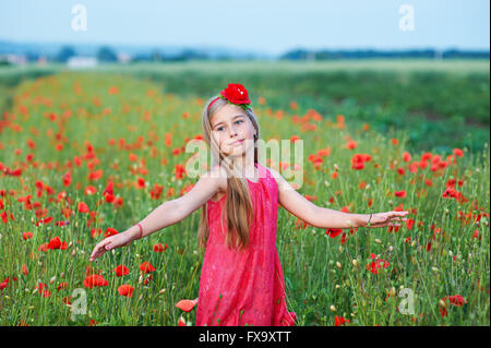 schöne Mädchen im roten Kleid geht im Mohnfeld Stockfoto