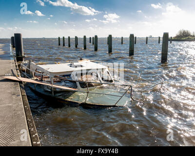 Halb versunkenen Motoryacht im alten Hafen mit Steg und Säulen, Niederlande Stockfoto