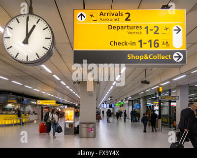 Zeichen, Uhr und Reisende im Terminal des Flughafen Schiphol, Niederlande Stockfoto