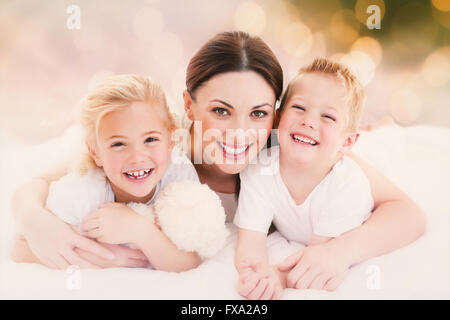 Zusammengesetztes Bild der glücklichen Mutter und ihre Kinder auf einem Bett liegend Stockfoto