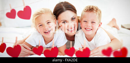 Zusammengesetztes Bild des Lachens Kinder spielen mit ihrer Mutter auf einem Bett liegend Stockfoto