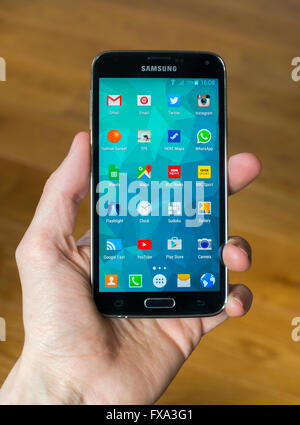 Eine Hand hält eine Samsung S5-Telefon mit dem home-Bildschirm geöffnet und zeigt apps. Stockfoto