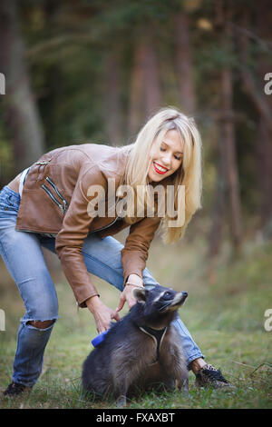 Porträt der attraktive junge Frau mit Waschbär in einem Wald Stockfoto