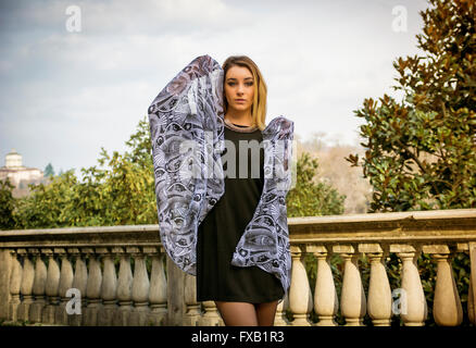 Porträt von attraktive blonde junge Frau im schwarzen Kleid, im freien Blick in die Kamera, das Spiel mit Schal oder foulard Stockfoto