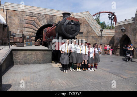 Junge Frauen gekleidet In British School Girl Uniformen Pose mit dem Hogwarts Schloss Express Zug Universal Studios Theme Park Stockfoto