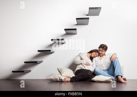 Paar zu Hause sitzen auf Treppen. Schwangerschaft Stockfoto