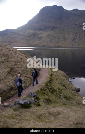 Zwei Fellwalkers nähert sich scheut Tarn mit dem Wainwright Harrison scheut auf die Skyline, Langdale, Cumbria UK. Stockfoto