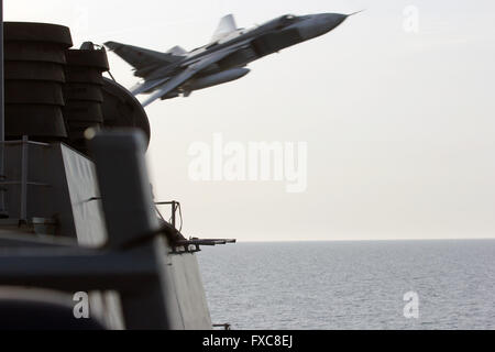 Eine russische Suchoi Su-24 Kampfflugzeuge macht einen sehr niedrigen Höhe über den Bogen von der US Navy Arleigh Burke-Klasse geführte Flugkörper Zerstörer USS Donald Cook während einer Patrouille 12. April 2016 in der Ostsee zu übergeben. Die aggressive Flugmanöver mit dem russischen Flugzeug simuliert einen Ziffernblocks Lauf. Stockfoto