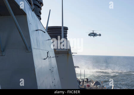 Ein russischen Kamov KA-27 HELIX Hubschrauber macht einen sehr niedrigen Höhe, während einer Patrouille 12. April 2016 in der Ostsee der US Navy Arleigh Burke-Klasse geführte Flugkörper Zerstörer USS Donald Cook übergeben. Die aggressive Flugmanöver mit dem russischen Flugzeug simuliert einen Ziffernblocks Lauf. Stockfoto