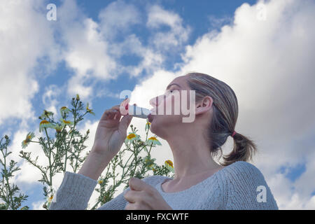 Junge Frau mit Inhalator zur Behandlung von Asthma allergisch auf Blumen Wiese Stockfoto