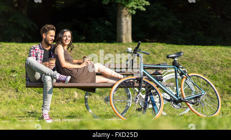 Freunde Rast unter der Sonne an einem Sommertag, Mannes Fahrrad im Vordergrund, werden sie mit Kaffee und ein gutes Gefühl Stockfoto