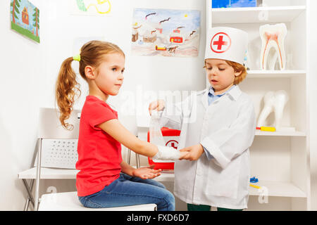 Kleine Kinderarzt Doktor Bandagierung des Mädchens arm Stockfoto