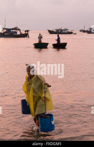 Wasser Träger Frau & Coracle Boote in der Morgendämmerung, Strand in Danang, Vietnam Stockfoto