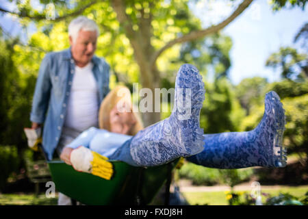 Älteres Paar spielen mit einer Schubkarre Stockfoto
