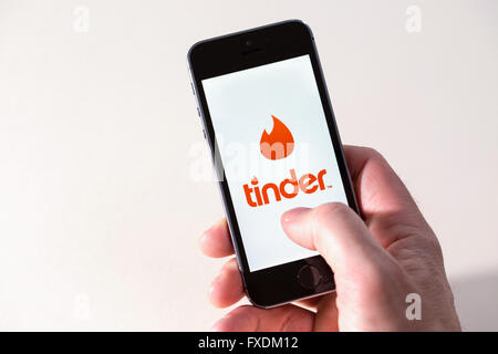 Ein Mann mit dem Zunder dating-app auf dem Handy Stockfoto