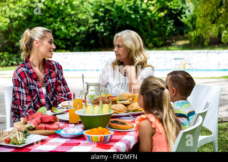 Kinder, die Mutter und Großmutter sprechen während dem Mittagessen zu betrachten Stockfoto