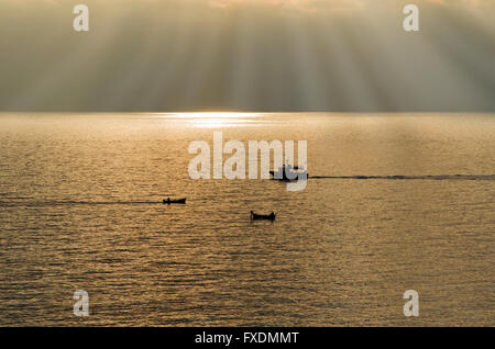 Cinque Terre Ligurien Italien, beleuchtete Boote kreuzen bei Sonnenuntergang auf der Unterseite, die Strahlen der Sonne durch die Wolken gehen Stockfoto