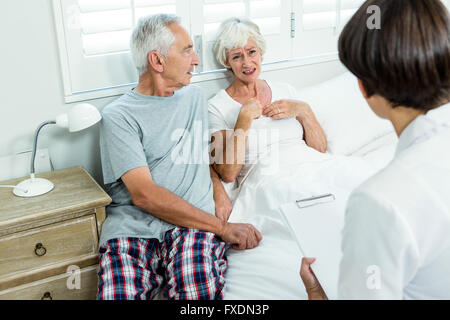 Ältere Frau mit Mann im Gespräch mit Ärztin Stockfoto