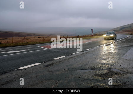 Ein Auto beschleunigt die A62 Strasse bei nasser Witterung in der Nähe von Marsden, Huddersfield, in Yorkshire Pennines, England, Großbritannien. Stockfoto