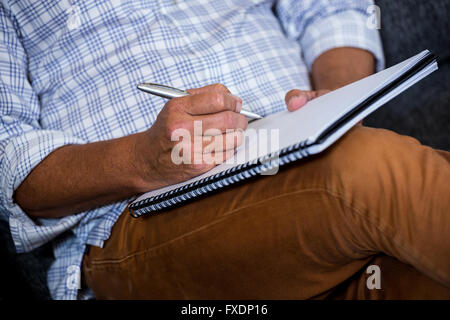 Mann schreiben Notizen im Tagebuch Stockfoto