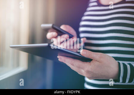 Smartphone- und Tablet-Daten-Synchronisation, Frau synchronisieren von Dateien und Dokumente auf drahtlose elektronische Geräte zu Hause, s Stockfoto