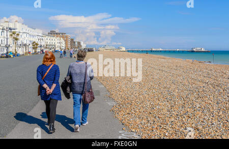 Paar Frauen zu Fuß entlang der Promenade am Meer an einem sonnigen Frühlingstag in Worthing, West Sussex, England, UK. Stockfoto