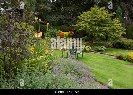 Ein privaten, traditionellen, gepflegten, ländlichen Garten, West Yorkshire, England - krautige Grenze, Blumen, Teich, gestreiften Rasen und Sitze. Stockfoto