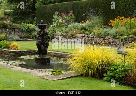 Einen privaten, traditionellen, gepflegten, ländlichen Garten, West Yorkshire, England - Rasen, Staudenrabatten, Teich und Brunnen. Stockfoto