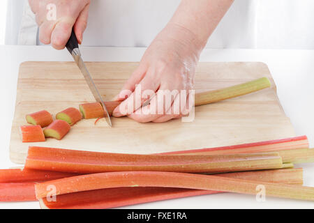 Hände schneiden Rhabarber in der Küche Stockfoto