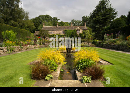 Einen privaten, traditionellen, gepflegten, ländlichen Garten, West Yorkshire, England - Teich, Brunnen und Rasen, mit dem Haus darüber hinaus. Stockfoto