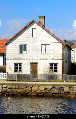 Lyckeby, Schweden - 7. April 2016: Alt und vernachlässigt am Flussufer Gebäude mit Holzzaun und dem Fluss vor. Stockfoto