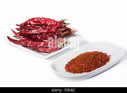 Studio-Fotografie-Bild von getrockneten roten Chilis und scharfem rotem Chilipulver isoliert auf weißem Hintergrund in diesem Lebensmittelfotografie-Foto von orientalischem Gewürz Stockfoto