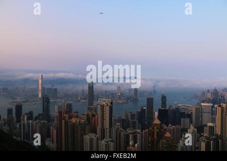 Hong Kong Skyline in einem schönen bewölkten Tag über Victoria Harbour. Flugzeug am Himmel Stockfoto