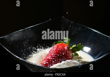 Reife Erdbeere fallen in eine Milch mit splash Stockfoto