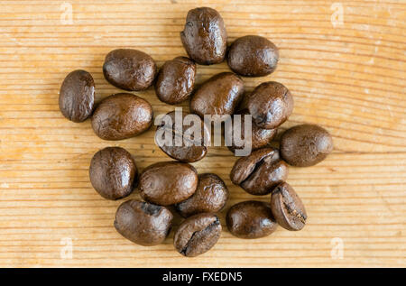 Nahaufnahme der mehrere ganze Braten Espresso Kaffee Bohnen auf eine Holzoberfläche. Stockfoto