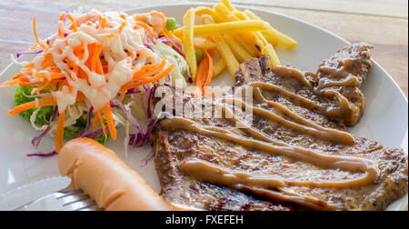 Schweinekoteletts Steak mit Salat und Pommes Frites auf weißen Teller, selektiven Fokus Stockfoto