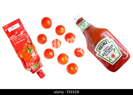 Eine Tube Tomatenmark, eine Flasche Tomatenketchup und Cherry-Tomaten vor weißem Hintergrund fotografiert. Stockfoto