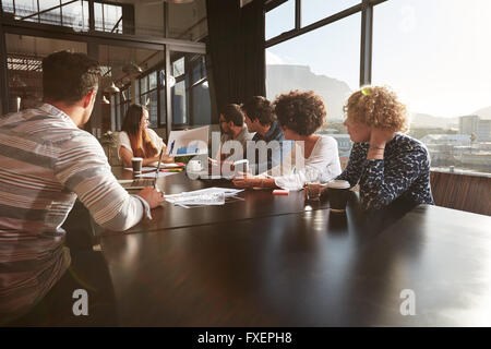 Junge Frau hält einen Vortrag an Kollegen im Büro. Gemischte Rassen Team von Kreativ-Profis in einem Meeting im Büro. Stockfoto