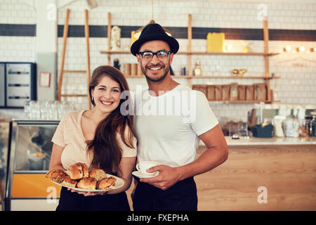 Porträt von glücklicher junger Mann und Frau mit Nahrung und Café im Coffee Shop. Paar beim Essen in einem Restaurant. Stockfoto