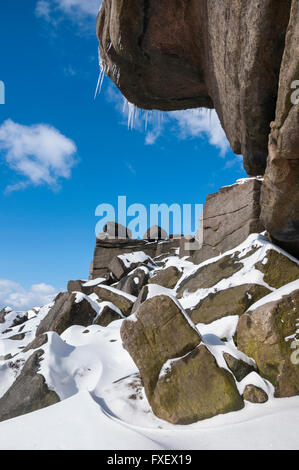 Eiszapfen hängen von Gritstone Felsen am Stanage Edge in Derbyshire auf einem eisigen, kalten Wintertag. Stockfoto