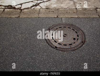 Abstrakte Kanaldeckel auf asphalt Stockfoto