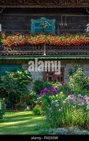 Altes Bauernhaus, Balkon mit Geranien (Pelargonium spec.), vor einem Blumengarten, Bauerngarten, Piesenkam, Isarwinkel Stockfoto