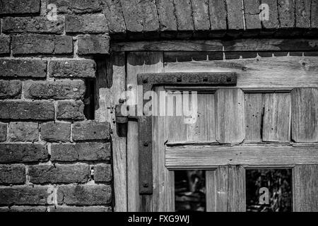 Defekte Tür mit fehlenden Platten, rostige Scharnier, alte Mauerwerk Stockfoto