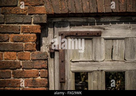 Defekte Tür mit fehlenden Platten, rostige Scharnier, alte Mauerwerk Stockfoto