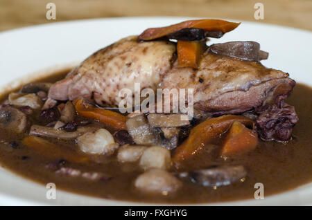 Coq Au Vin natürliches Licht in der Nähe von Seite. Klassische französische Gericht zubereitet Huhn in Rotwein mit Gemüse serviert Stockfoto