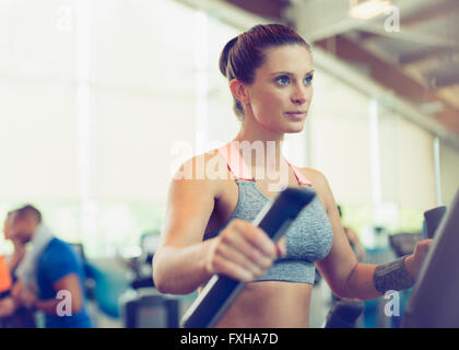 Fokussierte Frau Training auf Crosstrainer im Fitness-Studio Stockfoto