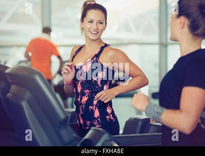 Lächelnde Frauen reden über Laufbänder im Fitness-Studio Stockfoto