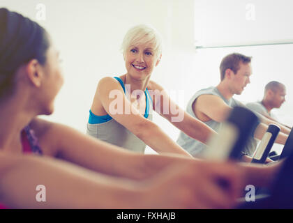 Lächelnde Frauen reden am Heimtrainer in Turnhalle Stockfoto
