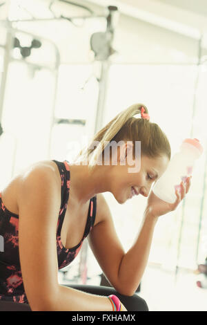 Müde Frau Kühlung Stirn mit Wasserflasche in Turnhalle Stockfoto